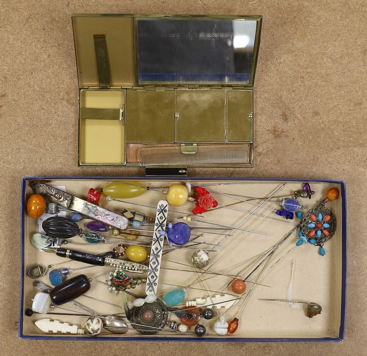 A collection of hat pins and a large enamel compact
